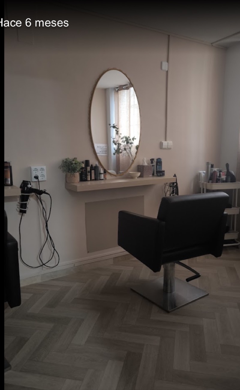 Interior del salón: sillón, espejo ovalado y suelo en espiga